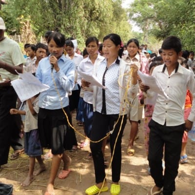 Students in Cambodia lead a community awareness event while walking through their village.