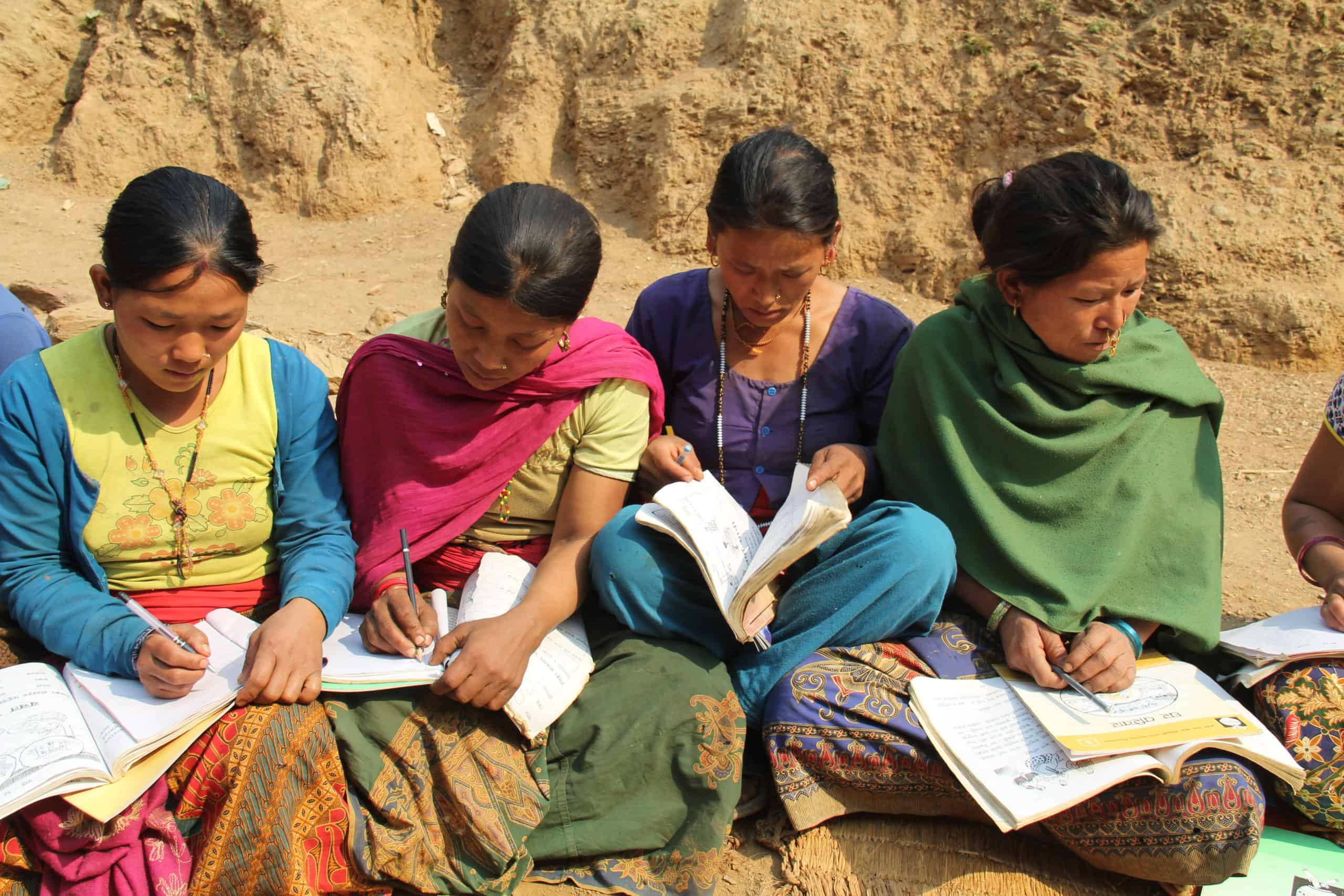 Women in Nepal sit in a circle to a class.
