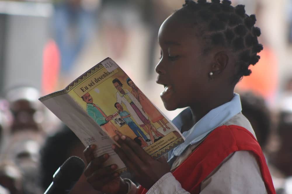 A child reads a loud a book for a community in Mozambique.