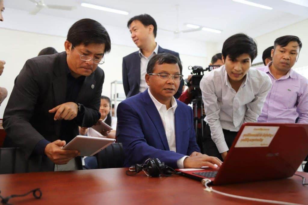 MoEYS Minister H.E. Hang Chuon Naron reviews online courses on the Moodle platform alongside Department of IT, ITC, and World Education staff.