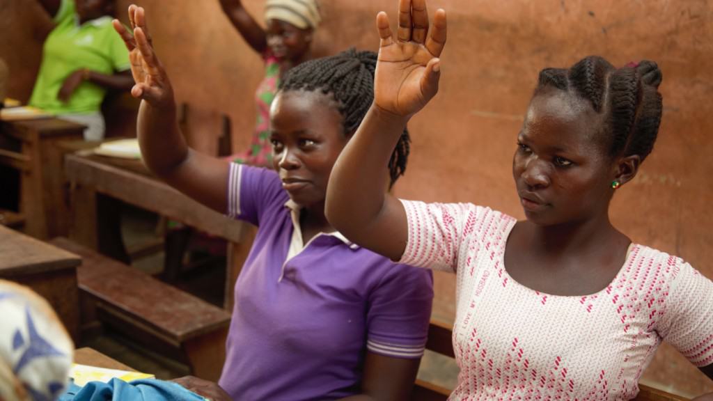 Girls raising their hands in a Strategic Approaches to Girls' Education (STAGE) project class.