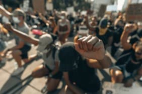 Group kneels with fists in the air at a Black Lives Matter rally.