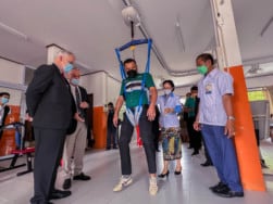 Man tests out the ceiling hoist for gait training that was provided to the center for medical rehabilitation in Laos by World Education, USAID, and the Okard project
