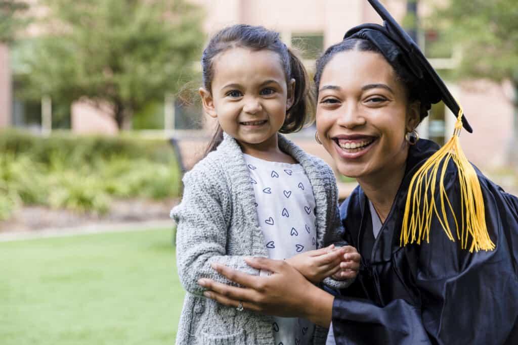 Mother in graduation cap and gown with child