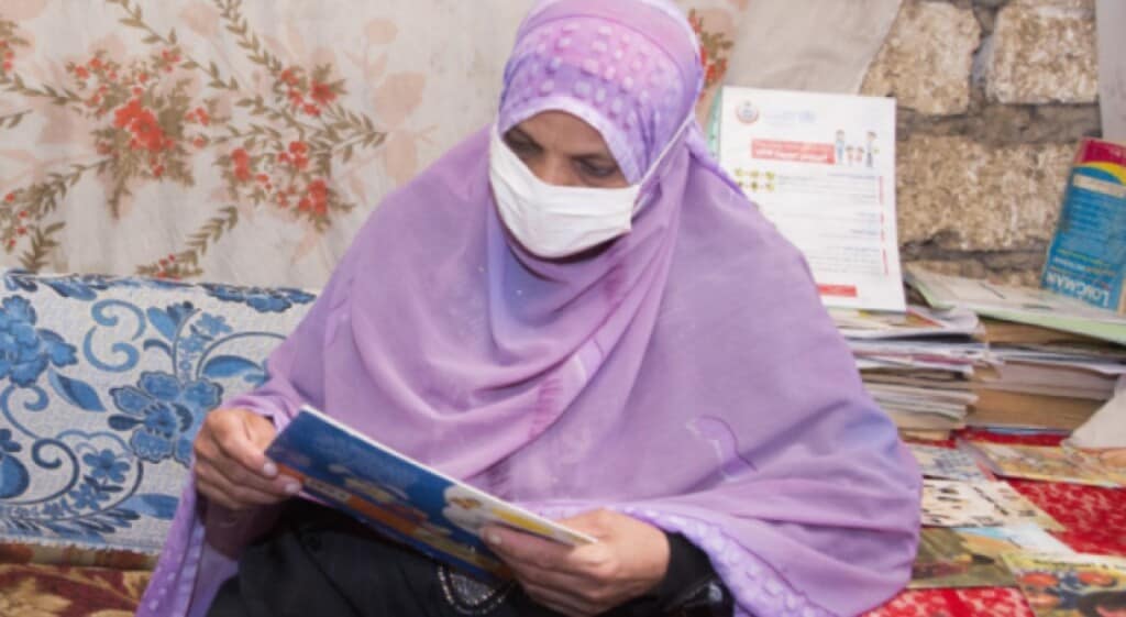 Egyptian woman in hijab wearing a mask reads a book