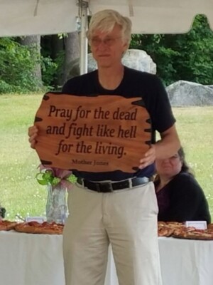 Art Ellison holding a sign that reads "Pray for the dead and fight like hell for the living".