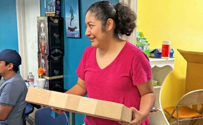 A woman holding a box with a laptop in it