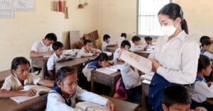 A teacher in Cambodia stands before her class reading from a book